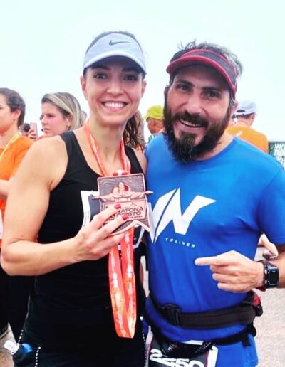 mulher e homem corredores da Meia Maratona do Cristo segurando a medalha